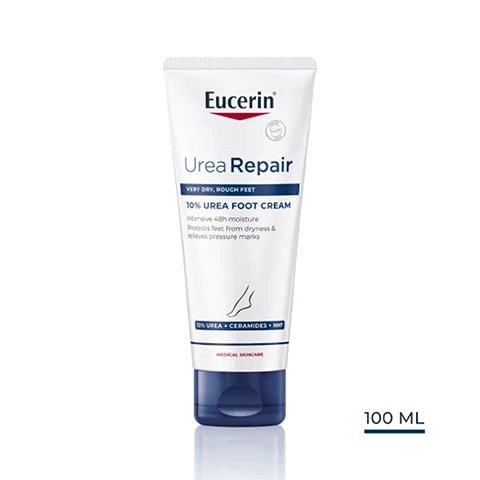 Image 1 - A tube of Eucerin Urea Repair 10% Urea Foot Cream with a white and blue design, labeled for very dry, rough feet, indicating it provides intensive moisture and relieves pressure marks, and includes the text 100 ML.
Image 2 - A smiling woman with shoulder-length hair showcases smooth skin while demonstrating benefits of a foot care product, which states intensive 48h moisture, protects feet from dryness, and relieves pressure marks.
Image 3 - A hand holds a tube of Eucerin Urea Repair Foot Cream, with the text indicating benefits for dry, rough skin, intense hydration, and suitability for feet.
Image 4 - A smooth, white cream droplet on a light background with labels indicating 10% Urea, Ceramides, and Natural Moisturizers.
Image 5 - A blue banner with soft light rays features the text 91% confirm* Even extremely dry, rough feet become smooth and supple again.
Image 6 - Image of three Eucerin Urea Repair products displayed in a row: a blue bottle labeled Shower Gel, a white bottle labeled 10% Lotion, and a tube labeled Foot Cream, with the title Recommended Routine above them.