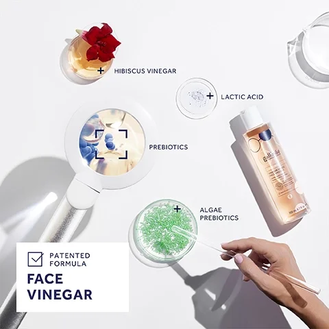 An image featuring a magnifying glass reflecting blueberries, surrounded by containers with hibiscus vinegar, lactic acid, and algae prebiotics, with the text PATENTED FORMULA FACE VINEGAR at the bottom.