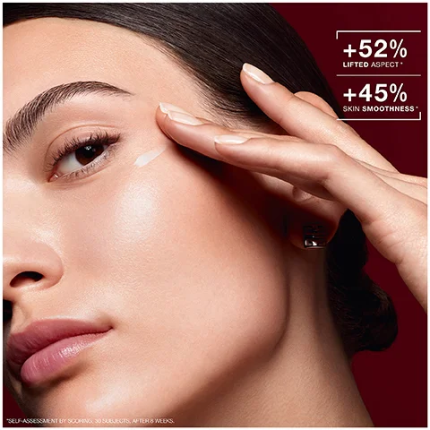 Image 1 - A close-up of a woman applying cream to her face, showcasing a smooth complexion and highlighted features, with visible text indicating +52% LIFTED ASPECT* and +45% SKIN SMOOTHNESS*.