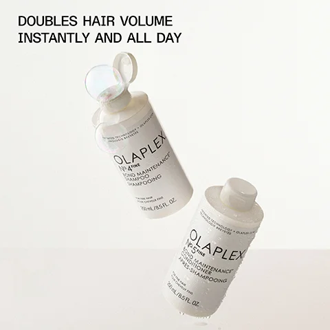 An image of two Olaplex hair care products, a shampoo bottle labeled Olaplex No. 4 Fine Bond Maintenance Shampoo and a conditioner bottle labeled Olaplex No. 5 Fine Bond Maintenance Conditioner, both appearing glossy with droplets of water and the text DOUBLES HAIR VOLUME INSTANTLY AND ALL DAY displayed above.