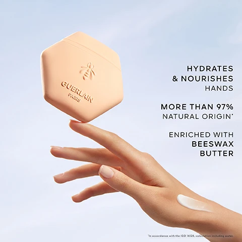 Image 1 - A hand holding a light pink hexagonal container of hand cream with the label Guerlain Paris and text stating hydrates & nourishes hands and more than 97% natural origin, enriched with beeswax butter.
Image 2 - A close-up image of vibrant orange mandarins and white basil flowers floating in clear water, with visible text reading MANDARIN, BASIL, GREEN TEA.
Image 3 - Aqua Allegoria fragrance bottle and a hexagonal cream container on a reflective surface, with text MANDARINE BASILIC SCENTED RITUAL and GUERLAIN PARIS.