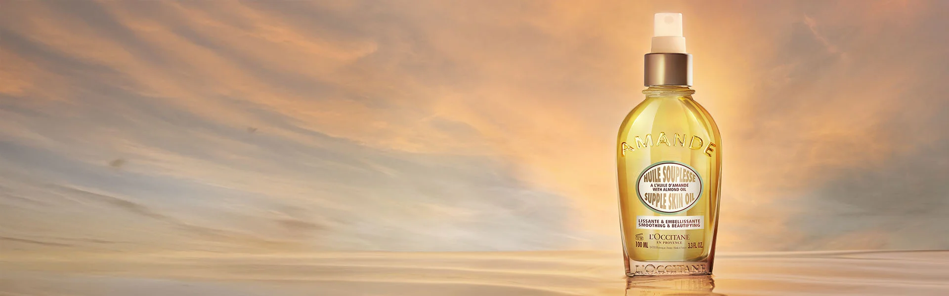 L'Occitane Almond Supple Skin Body Oil on a sunset background